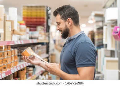 Bearded Man In Craft Store Selecting Paint For Work At Home