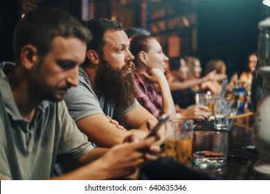 Bearded Man In Crowded Bar Watching Something