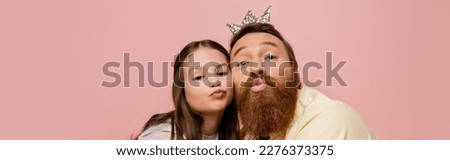 Bearded man with crown headband pouting lips near daughter isolated on pink, banner