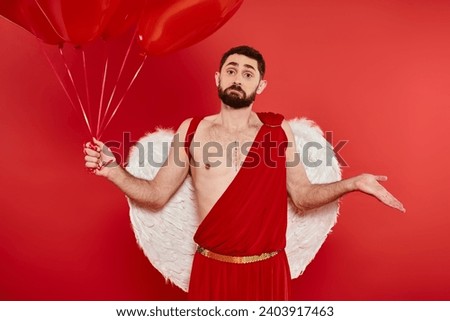 bearded man in cupid costume with heart-shaped balloons showing shrug gesture on red backdrop