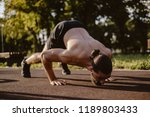 Bearded man doing dive bomber push ups in outdoor gym with face down on a sunny day