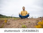 Bearded man doing yoga on a hill after hard working day. Concept of healthy lifestyle, retreat in nature, relaxation, connection with nature, meditation.