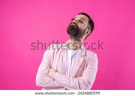 Bearded man dressed in a pink jacket with glasses. Emotional studio portrait.
