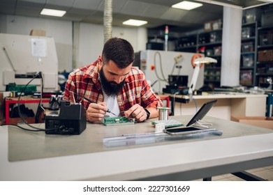 Bearded man electronics technician is soldering circuit board in his workshop. Computer support engineer. Modern technology. Repairing by hand. Copy space. - Powered by Shutterstock