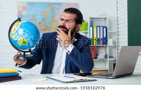 bearded man geographer work in classroom with map. prepare for exam. college lecturer on geography lesson. back to school. informal education. serious mature teacher looking at globe