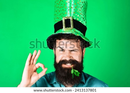 Bearded man in green top hat with clover in mouth showing sign ok. Saint Patrick's day celebration. National Irish holiday. Smiling man in Leprechaun hat with excellent symbol. Season sale. Discount.