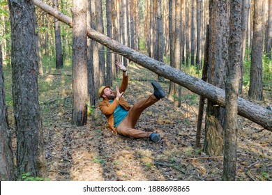 A Bearded Man In A Hat In The Forest A Tree Falls On Him, He Shouts And Put His Hand Forward Made A Frightened Face. Accident In The Woods