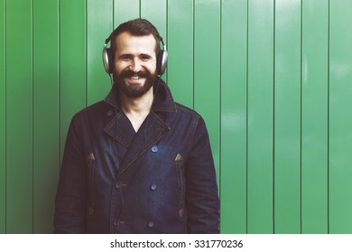 bearded man in headphones listening to music on green wall background with copyspace - Shutterstock ID 331770236