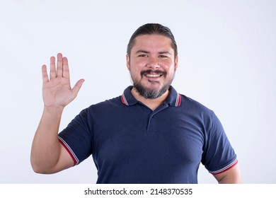 A Bearded Man In His 30s Saying Hi Or Swearing Loyalty. Wearing A Blue Polo Shirt. Isolated Against A White Background.