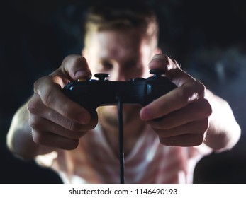 Bearded Man Holding Video Game Joystick Controller In Hands In Front Of Body At Home In The Night