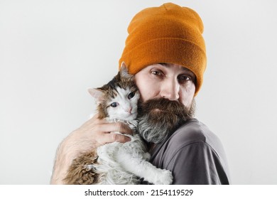 Bearded man hugging a cat. Hipster man in a hat and his beloved cat. - Shutterstock ID 2154119529