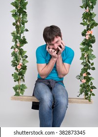 Bearded Man In Jeans, Swinging On Swings And Hamming To The Camera. Wooden Swing Suspended From A Rope Hemp, Rope Wrapped Vine And Ivy. Different Emotions