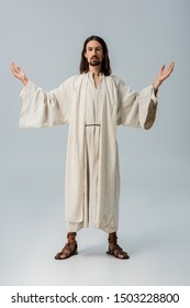 Bearded Man In Jesus Robe Standing With Outstretched Hands On Grey