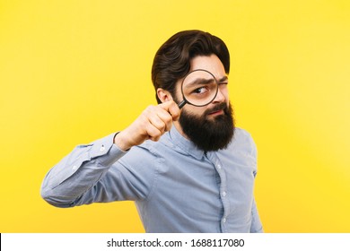 bearded man with magnifier over yellow  background, search concept