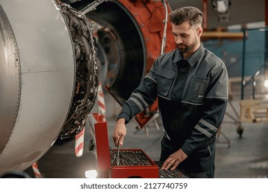 Bearded Man Maintenance Technician Grabbing Wrench From Tool Box While Standing Near Airplane At Repair Station