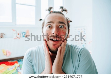 A bearded man with makeup is having a weird expression on his face. Humorous Make Up on Caucasian Man.