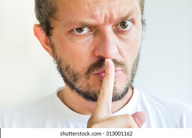 Bearded man making silence gesture, pst, shh, mean expression! 