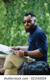 bearded man with a map in hand looking away