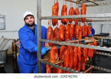 A Bearded Man A Meat-packing Plant Worker Carries A Rack With Hanging Meat Delicacies From Pork In A Tomato Marinade With Sesame Seeds