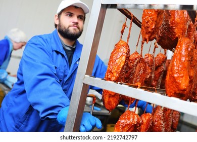 A Bearded Man A Meat-packing Plant Worker Carries A Rack With Hanging Meat Delicacies From Pork In A Tomato Marinade With Sesame Seeds