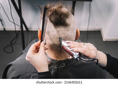 bearded man with a mohawk getting haircut by hairdresser while sitting in chair at barbershop. A hairdresser girl makes a mohawk to a guy. - Powered by Shutterstock