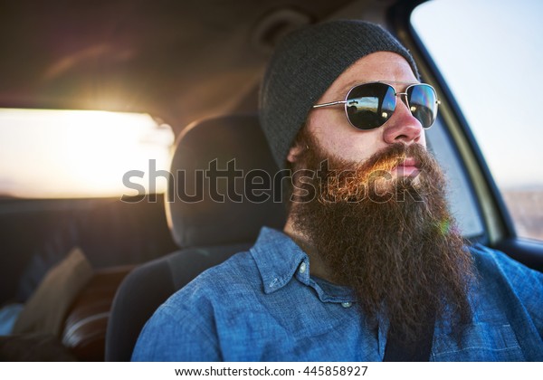 bearded man\
on road trip driving car with sun\
glasses