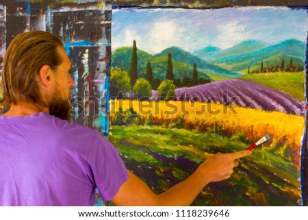 Bearded man painter artist draw with brush Lavender French summer rural landscape. French Tuscany. Field of red poppies, a field of yellow rye. Rural houses and high cypress trees on the hill.