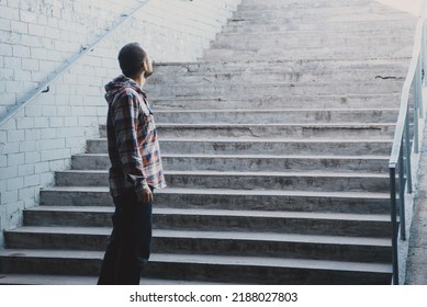A bearded man in a plaid shirt stands near the steps that lead up to the light. Loneliness and hope