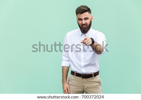 The bearded man pointing finger at camera and mockery over someone. Indoor, studio shot 