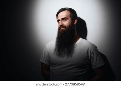 Bearded man portrait with dramatic side lighting creating deep shadows.