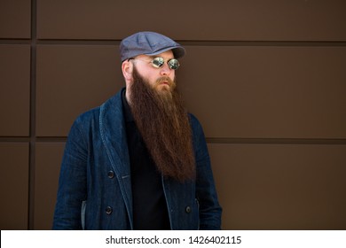 Bearded man. Portrait of an serious caucasian adult man with a very long beard in a cap and sunglasses on a sunny day outside.