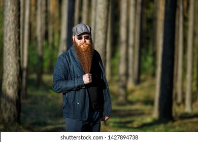 Bearded man. Portrait of an serious caucasian adult man with a very long beard in a cap and sunglasses on a sunny day outside in the forest.