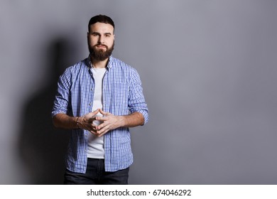 Bearded Man With Public Speaker Gesture. Fingers Connected At Fingertips, Pose Which Imposes Power And Patience, Gray Studio Background, Copy Space