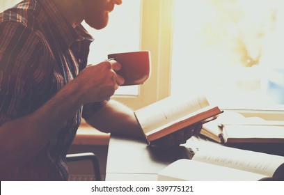 bearded man reading book with coffee or tea