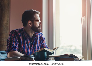 Bearded Man Reading Books At Table