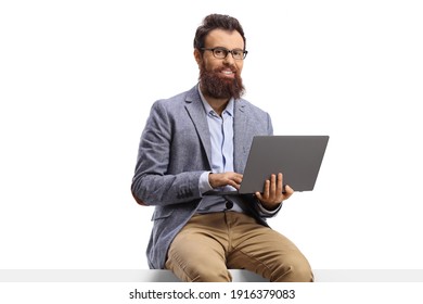 Bearded Man Seated On A Blank Panel With A Laptop Isolated On White Background