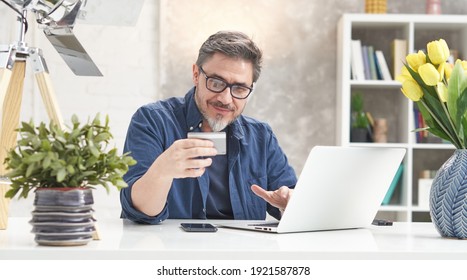 Gepflegter Mann online einkaufen mit Laptop-Computer und Bankkarte. Sitzen am Schreibtisch bestellen im Webshop, kostenpflichtig. Porträt des reifen Alters, mittleren Alters, mittleren erwachsenen Menschen in den 50ern.
