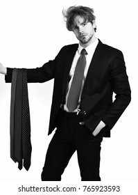 Bearded man, short beard. Caucasian stylish serious macho with moustache in elegant suit, red tie, shirt with suspenders holding dark ties posing at studio isolated on white background