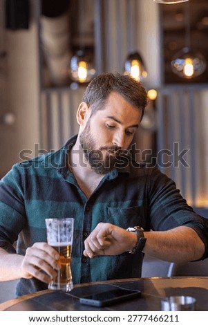 Bearded man sitting in a cafe and checking time on his watch