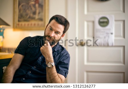 Bearded man sitting with hand on chin