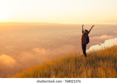 Bearded Man Standing At Foggy Lake In Sunset With Hands Up. 