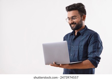 A BEARDED MAN STANDING WHILE WORKING ON LAPTOP