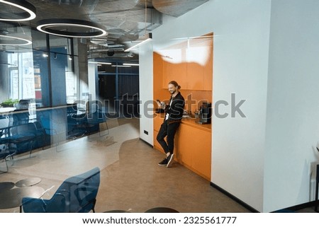 Bearded man stands at the kitchen area in coworking space