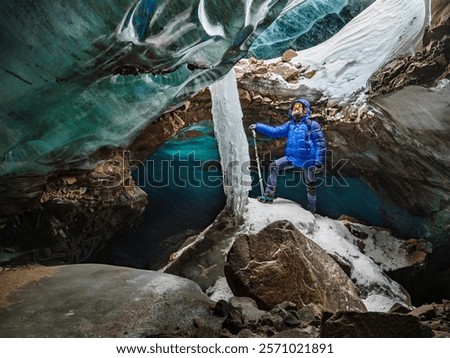 The bearded man is surrounded by bizarrely shaped blocks of ice that are a rich turquoise color. Incredible adventures in the mountains. Bogdanovich Glacier