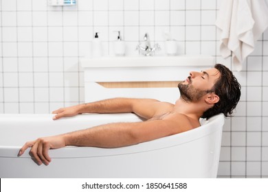 Bearded man taking bath with closed eyes at home - Shutterstock ID 1850641588