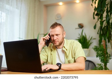 Bearded Man Talking Speaking On Phone Using Laptop. Male Employee Have Smartphone Call Cellphone With Client Or Business Partner.