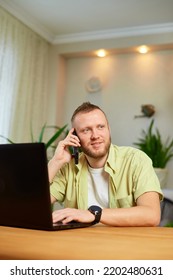 Bearded Man Talking Speaking On Phone Using Laptop. Male Employee Have Smartphone Call Cellphone With Client Or Business Partner.