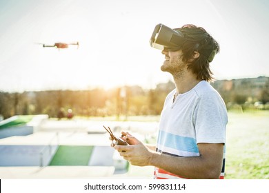 Bearded man using a drone with remote controller wearing virtual reality glasses making photos and videos - Young guy having fun with new vr technology trends - Focus on face headset - Warm filter