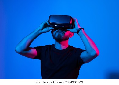 Bearded man in virtual reality headset communicate with a friends in a metaverse. Young man playing a vr video game. - Shutterstock ID 2084204842