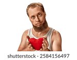 A bearded man in a white tank top holds a red plush heart with a quirky, wide-eyed expression. His playful and humorous look conveys awkward affection and carefree love. Happy and silly guy in Love.